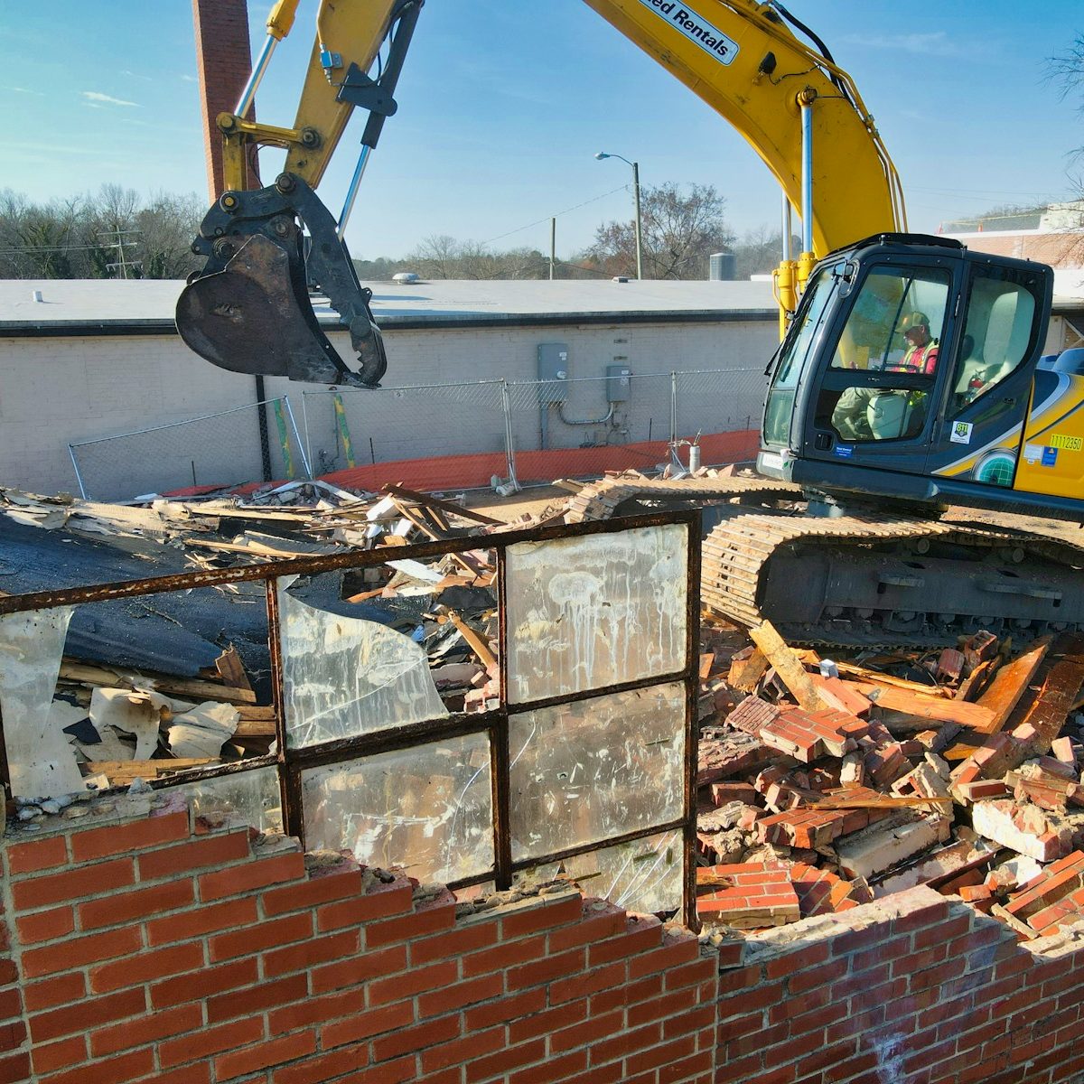 yellow and black excavator on brown brick wall during daytime